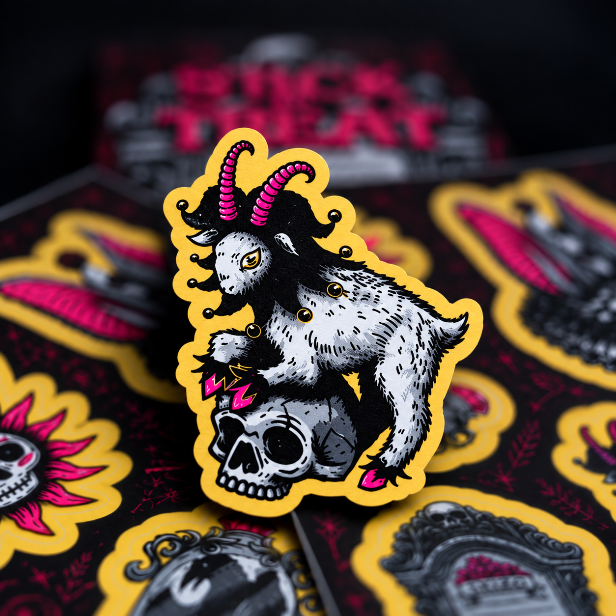 Une chèvre coiffée d'un chapeau de bouffon rose, debout sur un crâne, avec des stickers en arrière-plan.