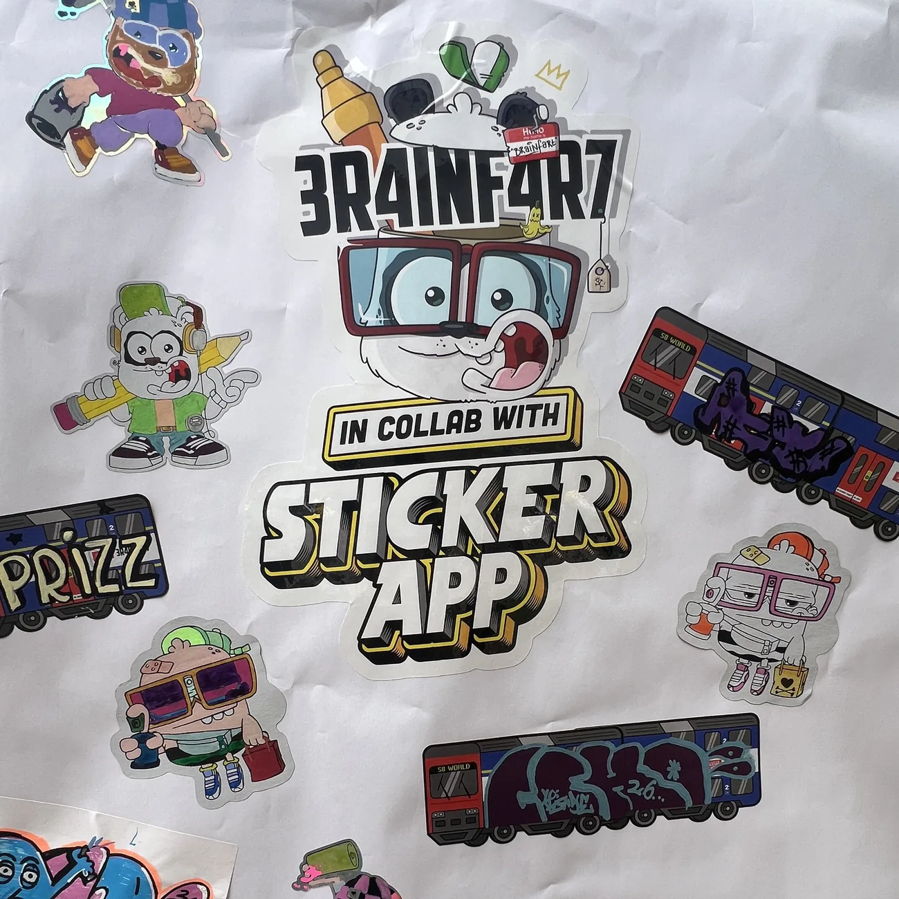 Mur couvert de stickers à la forme Brainfart x StickerApp coloriés à la main et d'étiquettes du train S8 World ornées de tags graffiti