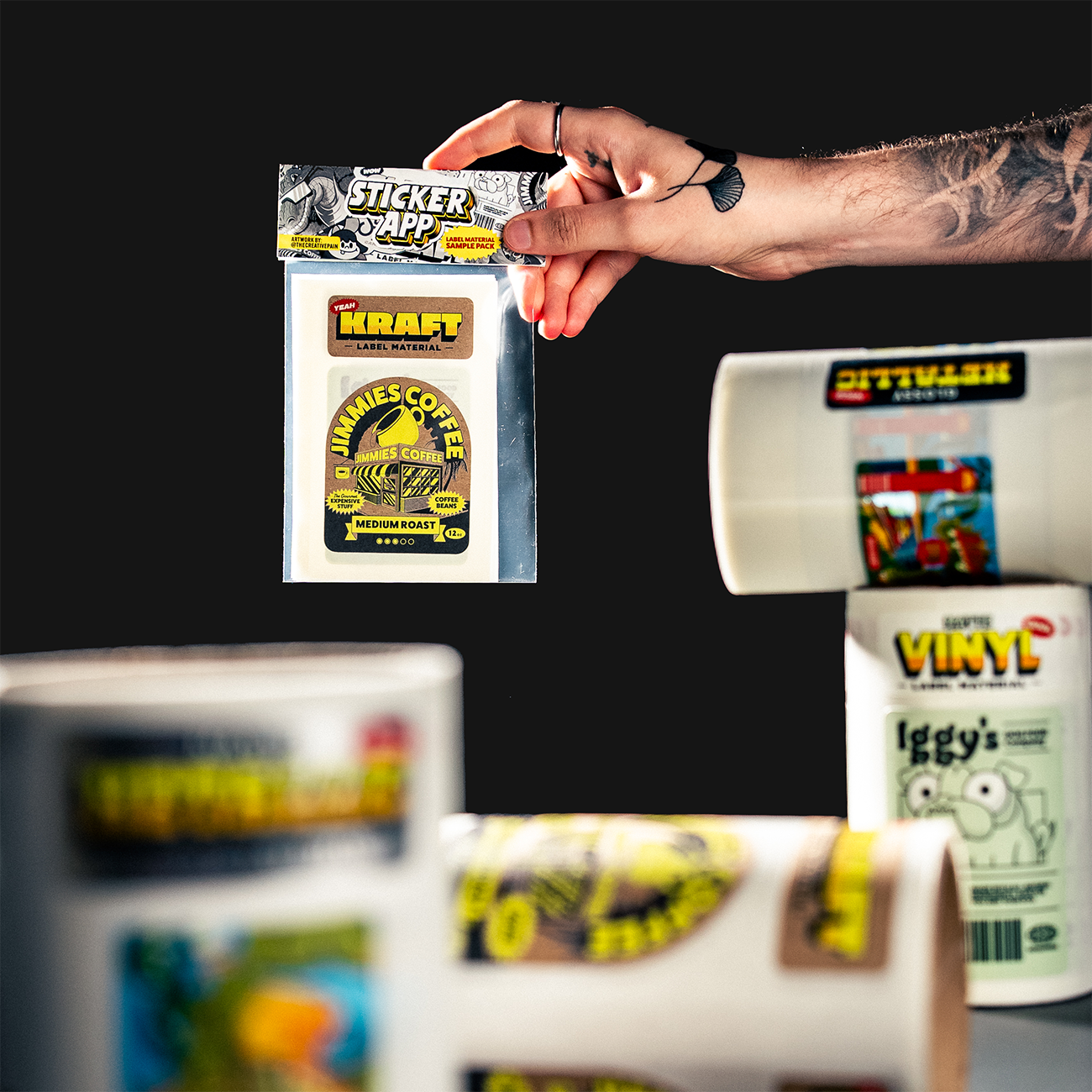 labels sample pack from stickerapp, with labels printed on all materials, with rolls in the foreground and a hand holding the pack