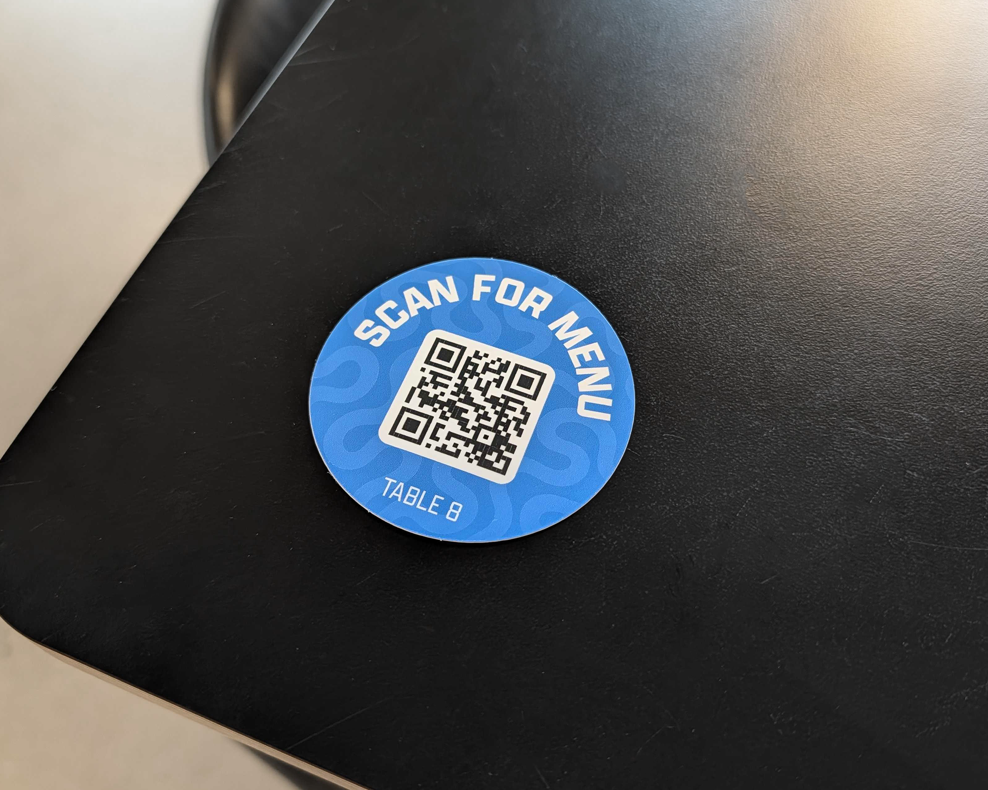 Sticker bleu avec QR code « Scan for menu » pour la table 8 sur une table noire