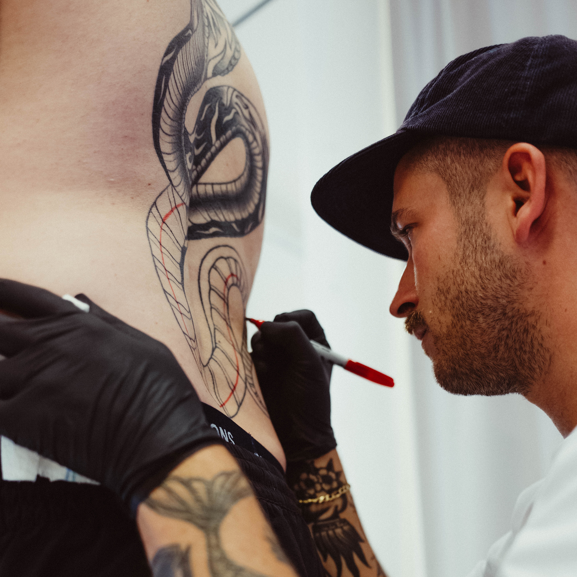 tatto artist broderson sketching a snake tattoo on back