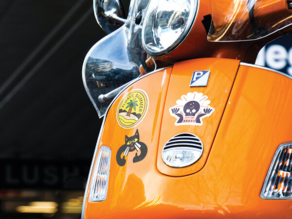 Several vinyl die cut stickers on a scooter.