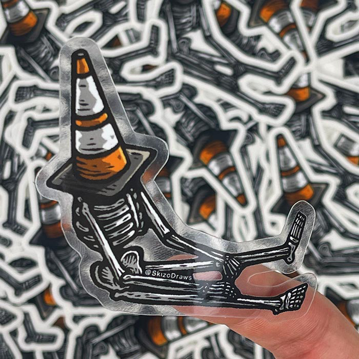 Sticker à la forme transparent représentant un squelette assis par terre, un cône de signalisation sur la tête, sur fond de stickers.