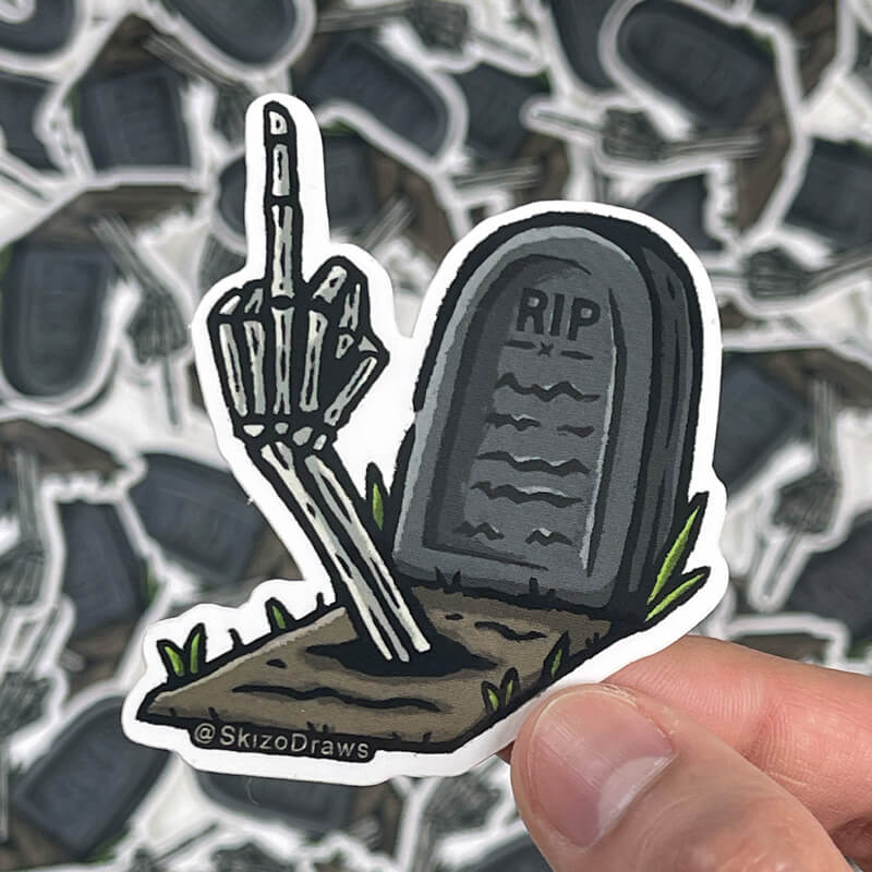 Sticker à la forme en vinyle représentant une tombe marquée « RIP » et un bras de squelette qui sort de terre en faisant un doigt d'honneur, sur fond de stickers.